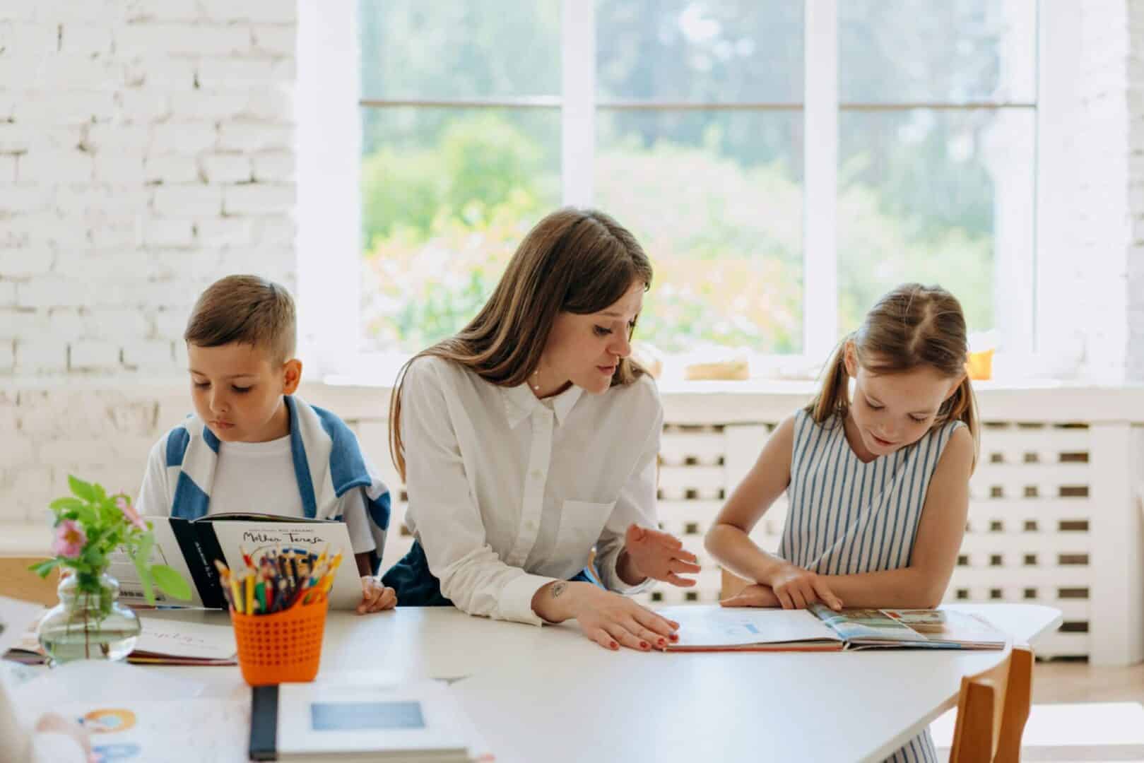 Registered Queensland teacher tutoring two primary school students at a table in Brisbane